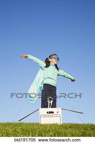 Stock Photography - Mixed race girl wearing cape and standing in box. Fotosearch
