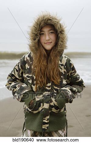 Stock Image - Mixed Race girl wearing jacket at beach. Fotosearch