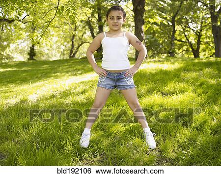 Stock Photograph - Mixed race girl with hands on hips in grass. Fotosearch