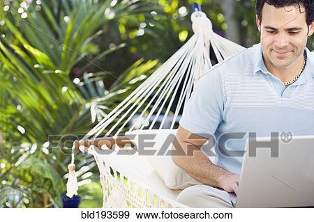 Mixed race man in hammock using laptop View Large Photo Image Stock Photo - Mixed race man in hammock using laptop. Fotosearch