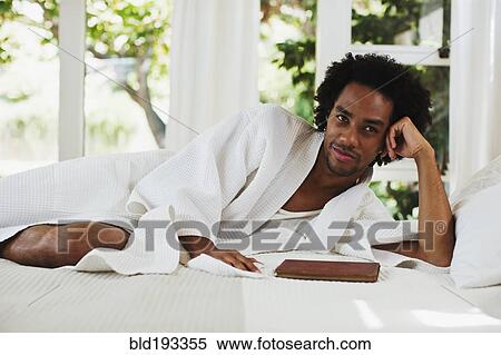 Mixed race man laying on bed reading View Large Photo Image Stock Photography - Mixed race man laying on bed reading. Fotosearch
