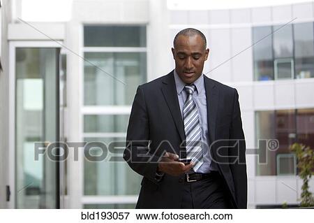 Stock Photo - Mixed race man looking at cell phone. Fotosearch