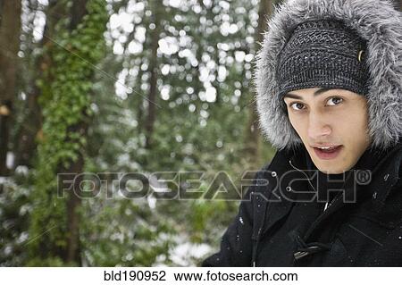 Stock Image - Mixed race man outdoors in hooded coat. Fotosearch