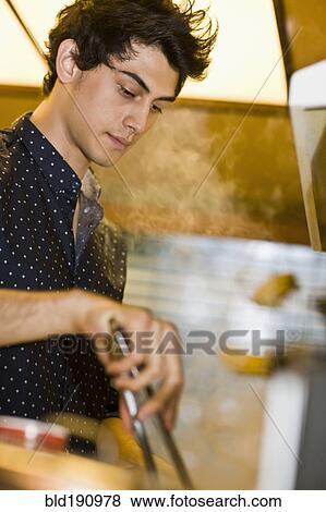 Stock Photo - Mixed race man preparing food in kitchen. Fotosearch