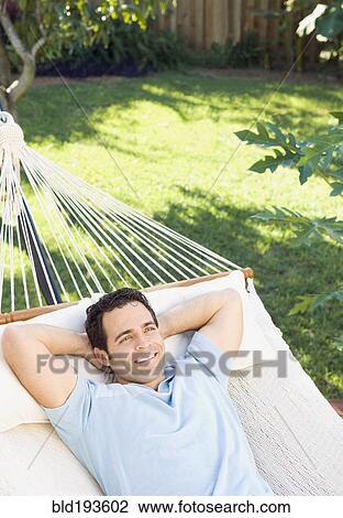 Stock Image - Mixed race man relaxing in hammock. Fotosearch
