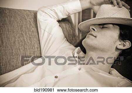 Mixed race man sleeping on sofa with hat over face View Large Photo Image Stock Image - Mixed race man sleeping on sofa with hat over face. Fotosearch