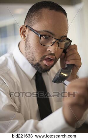 Stock Image - Mixed race man talking on telephone. Fotosearch