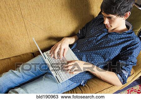 Mixed race man typing on laptop on sofa View Large Photo Image Stock Image - Mixed race man typing on laptop on sofa. Fotosearch