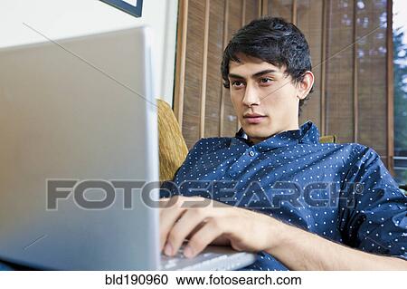 Stock Image - Mixed race man typing on laptop. Fotosearch