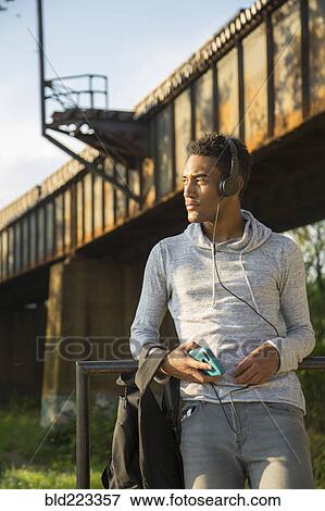 Stock Photo - Mixed Race man with backpack listening to headphones. Fotosearch