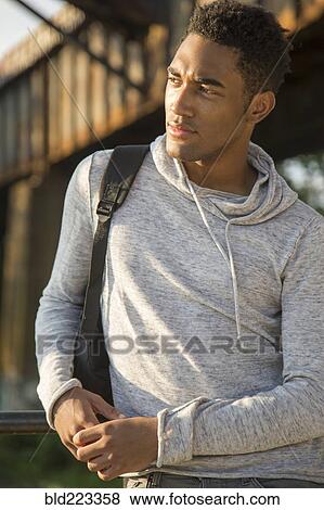 Mixed Race man with shirt draped over shoulders listening to headphones View Large Photo Image Stock Photo - Mixed Race man with shirt draped over shoulders listening to headphones. Fotosearch