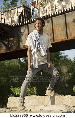 Mixed Race man with shirt draped over shoulders listening to headphones View Large Photo Image Stock Photography - Mixed Race man with shirt draped over shoulders listening to headphones. Fotosearch