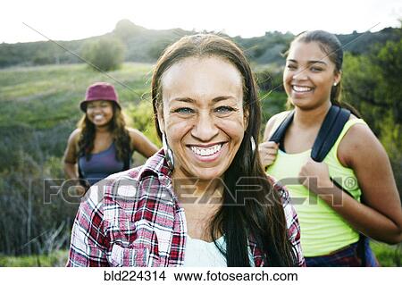 Mixed Race mother and daughters backpacking in field View Large Photo Image Picture - Mixed Race mother and daughters backpacking in field. Fotosearch