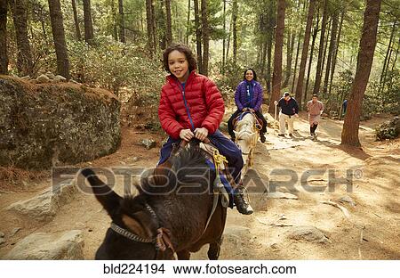Picture - Mixed Race mother and son riding horses. Fotosearch