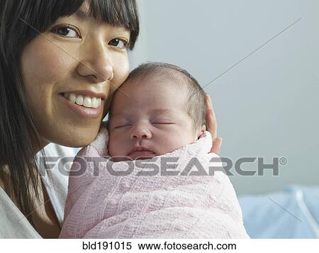 Stock Photography - Mixed race mother cuddling newborn baby. Fotosearch