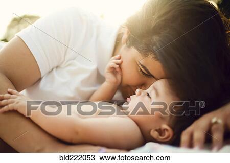 Stock Image - Mixed race mother nuzzling baby. Fotosearch