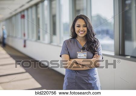 Stock Photograph - Mixed race nurse smiling in hospital hallway. Fotosearch