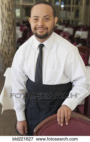Stock Photo - Mixed race server with down syndrome smiling in restaurant. Fotosearch