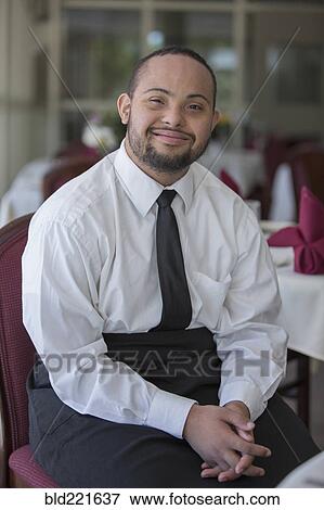 Stock Photo - Mixed race server with down syndrome smiling in restaurant. Fotosearch