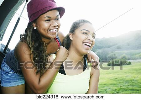 Mixed Race sisters at hatch of car laughing View Large Photo Image Stock Photo - Mixed Race sisters at hatch of car laughing. Fotosearch