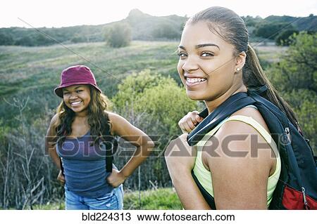 Mixed Race sisters backpacking in field View Large Photo Image Stock Image - Mixed Race sisters backpacking in field. Fotosearch