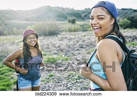 Mixed Race sisters backpacking in field View Large Photo Image Stock Photo - Mixed Race sisters backpacking in field. Fotosearch