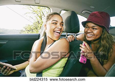 Stock Photography - Mixed Race sisters laughing in car. Fotosearch