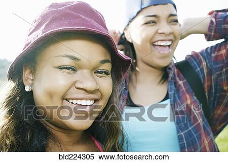 Stock Photography - Mixed Race sisters laughing outdoors. Fotosearch