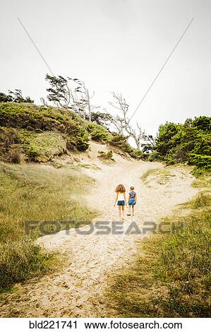 Stock Image - Mixed race sisters walking on beach. Fotosearch