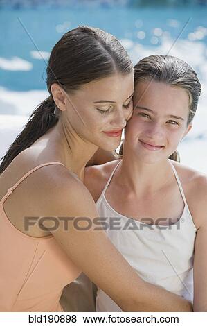Stock Photo - Mixed race woman and daughter in bathing suits hugging. Fotosearch