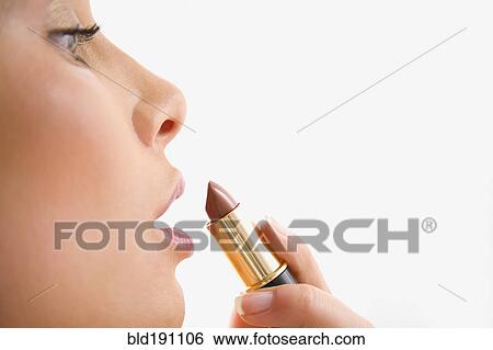Stock Photograph - Mixed race woman applying lipstick. Fotosearch