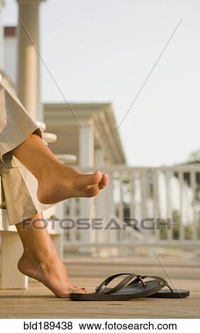 Stock Photo - Mixed race woman barefoot near flipflops. Fotosearch