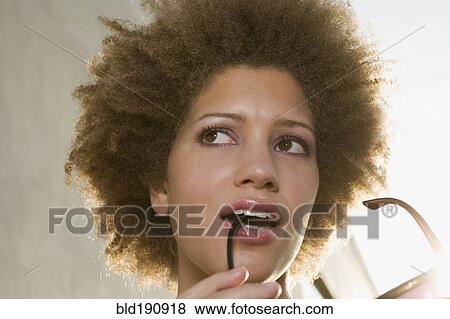 Stock Photo - Mixed race woman biting on sunglasses. Fotosearch