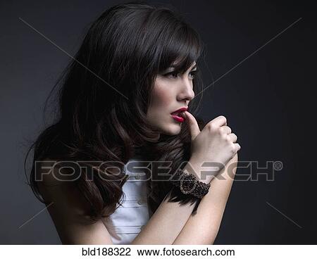 Stock Image - Mixed Race woman biting on thumb. Fotosearch
