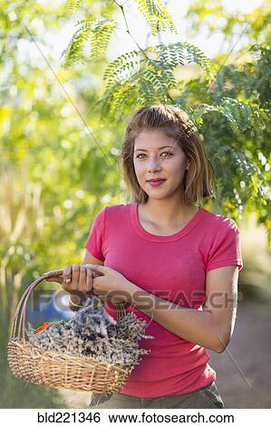 Stock Photograph - Mixed race woman carrying basket of flowers. Fotosearch