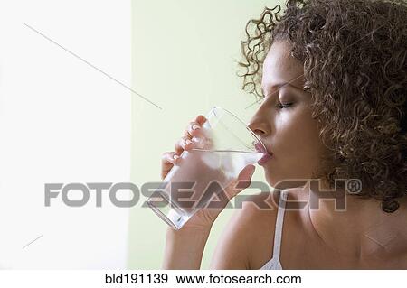 Stock Photo - Mixed race woman drinking glass of water. Fotosearch