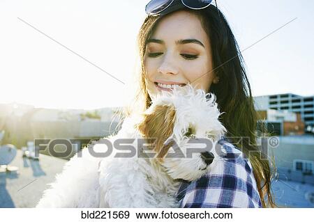 Mixed race woman holding dog on urban rooftop View Large Photo Image Stock Photo - Mixed race woman holding dog on urban rooftop. Fotosearch