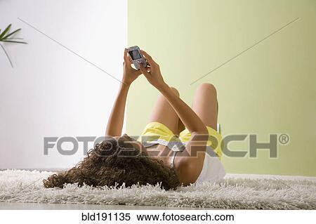 Mixed race woman laying on floor looking a cell phone View Large Photo Image Stock Photography - Mixed race woman laying on floor looking a cell phone. Fotosearch