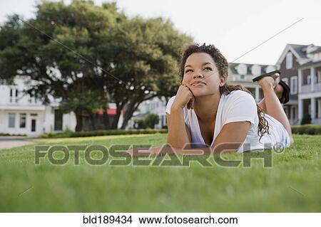 Picture - Mixed race woman laying on grass. Fotosearch