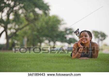 Mixed race woman laying on grass using cell phone View Large Photo Image Stock Image - Mixed race woman laying on grass using cell phone. Fotosearch