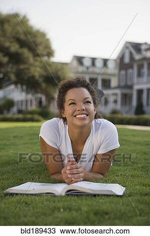 Mixed race woman laying on grass with book View Large Photo Image Stock Image - Mixed race woman laying on grass with book. Fotosearch