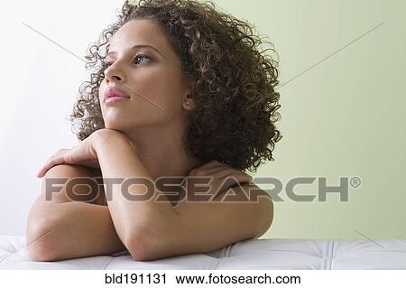 Stock Image - Mixed race woman laying on sofa. Fotosearch