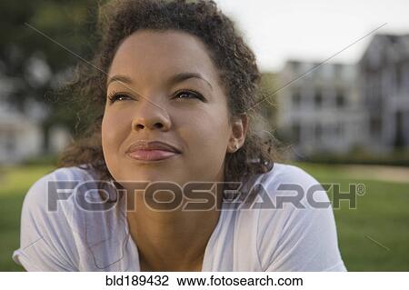 Stock Image - Mixed race woman looking up outdoors. Fotosearch