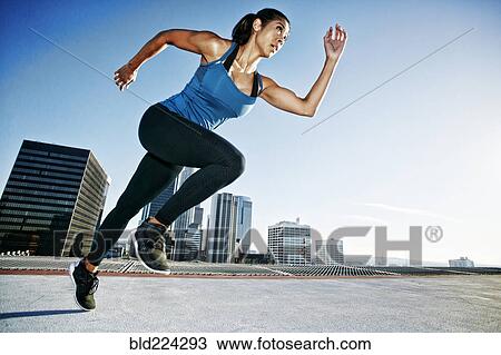 Stock Image - Mixed Race woman running on urban rooftop. Fotosearch