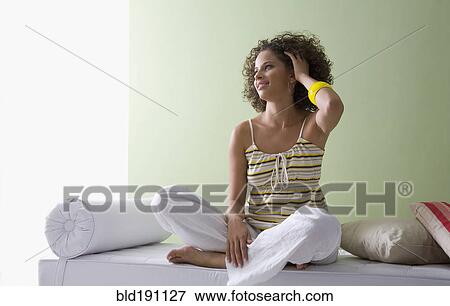 Mixed race woman sitting cross-legged on sofa View Large Photo Image Stock Photo - Mixed race woman sitting cross-legged on sofa. Fotosearch