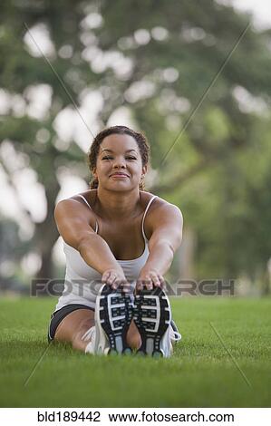 Mixed race woman sitting on grass stretching View Large Photo Image Stock Image - Mixed race woman sitting on grass stretching. Fotosearch