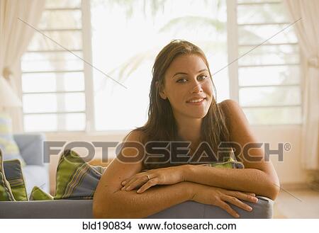 Picture - Mixed race woman sitting on sofa in living room. Fotosearch