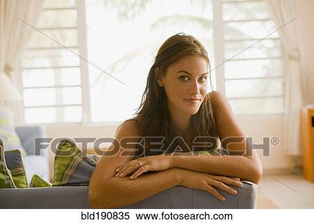 Stock Photography - Mixed race woman sitting on sofa in living room. Fotosearch