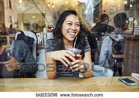 Stock Photo - Mixed Race woman smiling in cafe window. Fotosearch
