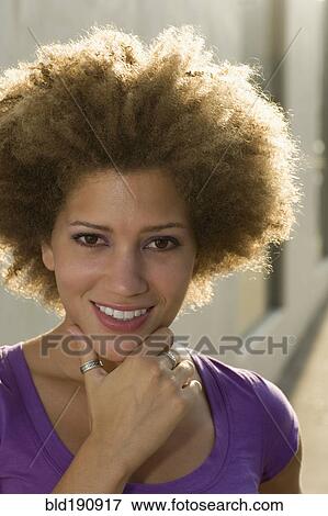 Stock Photo - Mixed race woman smiling with head in hands. Fotosearch